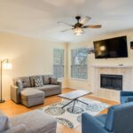 A modern vacation rental property with a laptop showing pricing analytics, surrounded by icons representing seasonality, location, demand, reviews, and dynamic pricing.